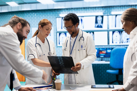 Diverse licensed medics working together to put the right diagnosis after examining x ray test results in medical cabinet. Physicians experts ensuring disease prevention and treatment.の写真素材