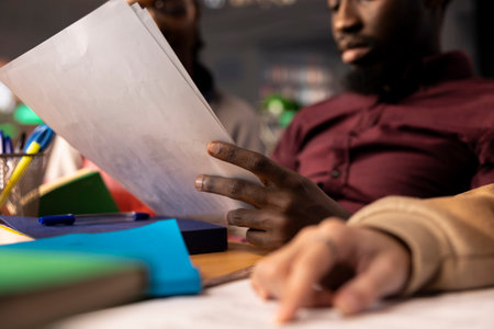 Young diverse adults in a campus library brainstorming ideas for a startup, enhancing their knowledge of business administration and corporate strategies to work on a class project. Close up.の写真素材
