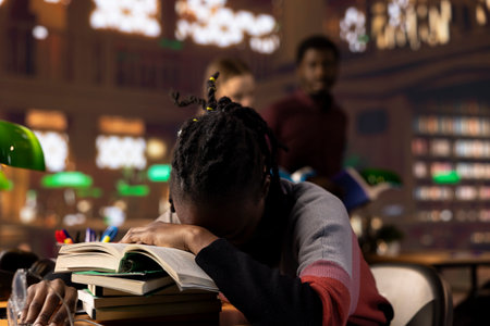 African american pupil sleeping on her books pile after a long night of studying, struggling to...