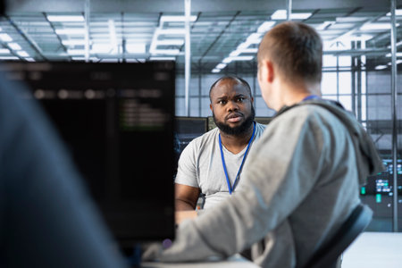 Manager discussing with developer after making error affecting high tech data center. Supervisor...