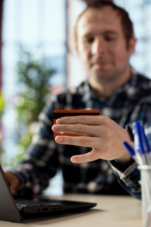 Close up of credit card used by shopper doing online payments during checkout process. Focus on...