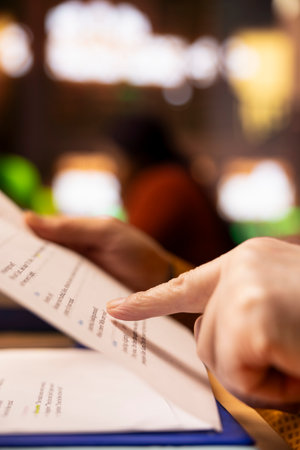 Mature person reading in a public library under a green lamp, deeply focused on studying documents, pursuing senior education and expanding his academic qualifications. Close up.の写真素材