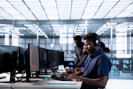 Man in data center workplace hearing songs in headset while using programming languages to build applications. Server hub software developer listening music, debugging codeの写真素材