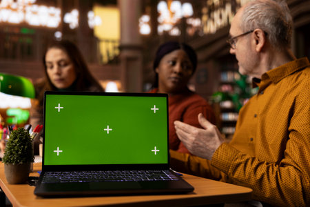 Multiethnic group of people studying together at library next to mockup display, engaged with academic text and paperwork. Working on their degree in a serene public library environment.の写真素材