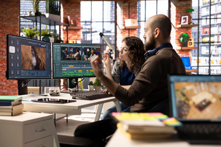 Video editors couple working as a team for a freelance video shoot, editing and mixing video clips in post production using filmmaking software. Talented people work on a music video.の写真素材