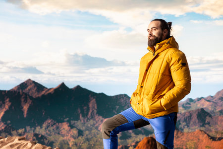 Hiker takes a moment to admire the panoramic view of mountains, looking into the distance and...