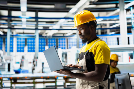 Photovoltaics factory engineer using laptop to do performance testing of solar panel production line. Technician improving sustainable solar energy configurations for cost reduction.の写真素材
