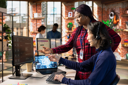 Call center supervisor guiding intern on how to use AI chatbot app on computer. African american...