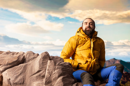 Male hiker looks out over a breathtaking mountain range from the hill top, embracing the solitude...