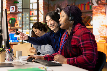 Happy customer service senior manager teaching new employee how to track support tickets in company...