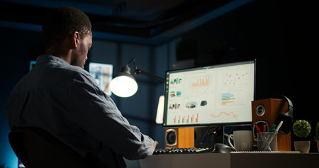 Network analyst studying digital commerce progression reports on computer, working at home to boost earnings and gain shareholder backing. Specialist analyzes company information. Camera A.の写真素材