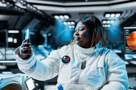 Female astronaut doing videocall, talking with family, presenting space station. African american...