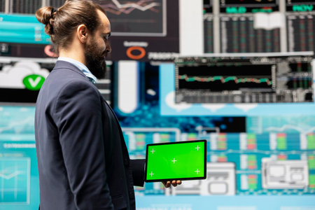 Male expert uses tablet with chroma key display leveraging dashboards, financial trends and KPI...