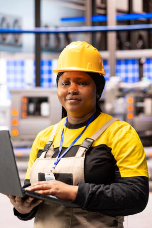 African american technician overseeing production line in smart manufacturing plant, checking...