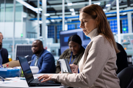 Factory employee works on laptop next to executives discussing solar panel automation strategies....