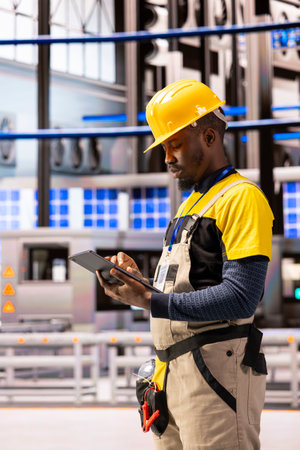 Male engineer analyzing industry 4.0 system performance in smart manufacturing plant. Black man...