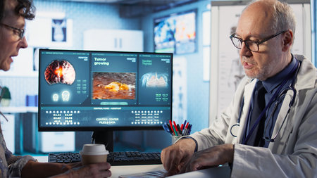 Specialist and old woman discuss x ray scan for preventive cancer medicine and health awareness. Cancer expert provides a geriatric patient with insights into tumor risks. Camera A.の写真素材