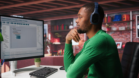 Freelance developer writing code in a modern programming language. Young man analyzes big data, algorithms and optimizing performance while using binary code at home office. Camera B.の写真素材