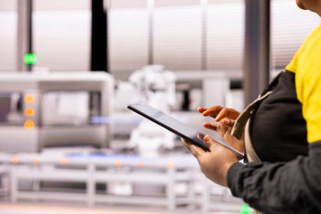 High tech industrial plant specialist programs and refines robot arm automation processes, using digital interface to enhance production efficiency. Professional engineer upgrading industry 4.0 systemの写真素材