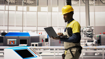 Engineer inspecting solar panel production lines using laptop, analyzing equipment performance, maintaining photovoltaic assembly systems in automated eco friendly factory, camera Aの写真素材