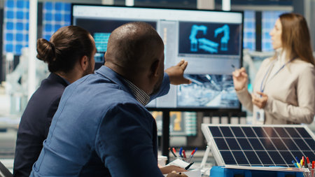 Executives and investors in photovoltaics plant reviewing solar technology reports, discussing future investment opportunities in renewable energy manufacturing, camera Bの写真素材