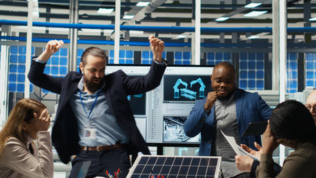 Happy businessmen in solar panel plant celebrating increased sales after newly developed innovative prototypes. Cheerful factory researching team excited by work done, dancing from joy, camera Bの写真素材