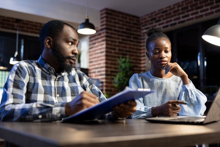 Black businessman and woman collaborate on investment strategies, discussing forex market fluctuations. The professional office setting reflects their dedication to trading and financial planning.の写真素材