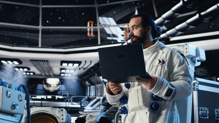 Astronaut reviewing onboard analytics on laptop before stepping out for scheduled operations outside space station. Cosmonaut verifying mission parameters after landing on alien planetの写真素材
