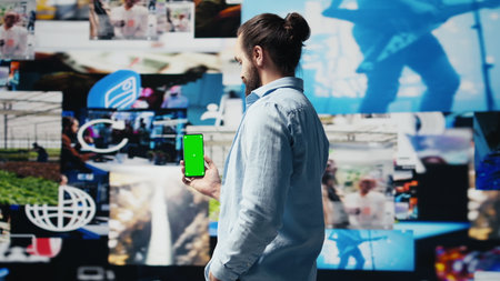 Young adult holds phone with chroma key screen and connecting on socials, using his imagination and modern e commerce skills to connect with people online. Entertainment. Camera B.の写真素材