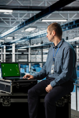 Engineer using chroma key laptop in server hub, conducting hardware installations and upgrades. Data center employee using green screen notebook, implementing server virtualization solutionsの写真素材