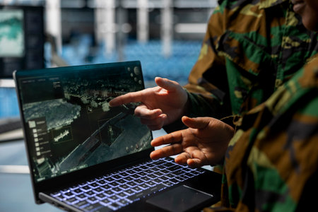 Close up of army experts in data center analyzing infrared surveillance feed on tactical interface. Military units operating real time satellite reconnaissance from secure server roomの写真素材