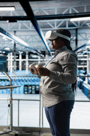 Server room engineer visualizing AI model outputs using VR gear, managing infrastructure systems. Data center worker using virtual reality technology, running artificial intelligence software testsの写真素材