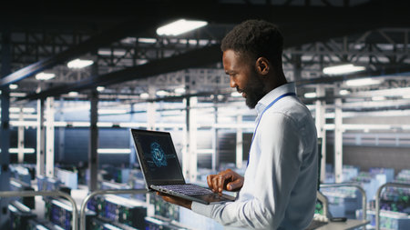 Programmer and colleague in data center reviewing AI LLM visualizations on laptop. IT teamworking coworkers analyze neural network performance outputs to ensure stable infrastructure operationsの写真素材