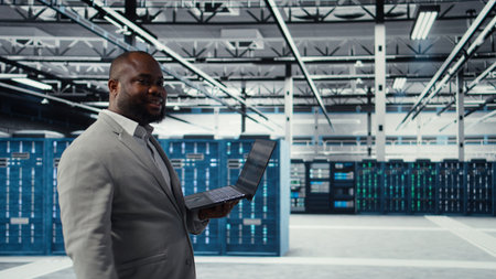 Data center engineer deploying AI driven management tools using laptop. Server farm employee...
