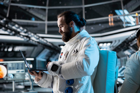 Astronaut researcher verifying navigation coordinates using laptop, carrying out research. Scientist wearing cosmonaut gear in spaceship monitoring life support systems during flightの写真素材