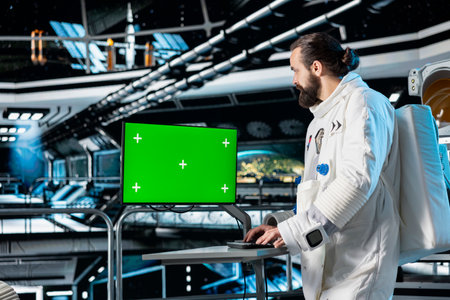 Astronaut in starship using green screen monitor to confirm suit integrity. Orbital station crew...