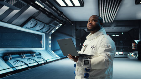 Astronaut in spacecraft using laptop to run telemetry data analysis. Man in spaceship wearing spacesuit analyzing mission logs on notebook during planetary exploration, camera Aの写真素材