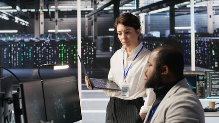 Happy data center manager providing positive feedback to engineer developing neural networks software on computer. Cheerful supervisor pleased by employee work implementing AI in server room, camera Aの写真素材