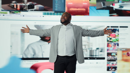 Overjoyed man with open arms facing large digital video wall expressing happiness, benefiting from endless entertainment selection. Joyful viewer enjoying access to endless streaming options, camera Aの写真素材