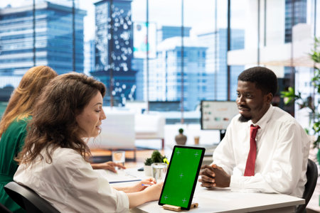 HR worker implementing diversity recruitment strategy for company, using chroma key tablet. Recruiter reaching agreement with african american man, using isolated screen key deviceの写真素材