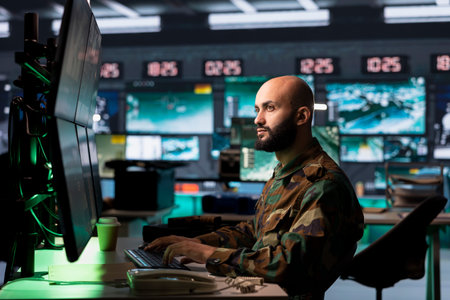 Counterterrorism division officer in command center using target acquisition tech to detect enemy location. Middle Eastern defense security agent using satellite equipment to track threatsの写真素材
