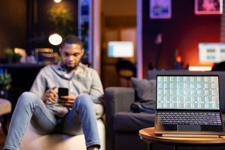 Black adult monitoring a screen to review stock market online data, reviewing day trading strategies and financial diagrams. Remote worker tracks online investments and economic trends.の写真素材