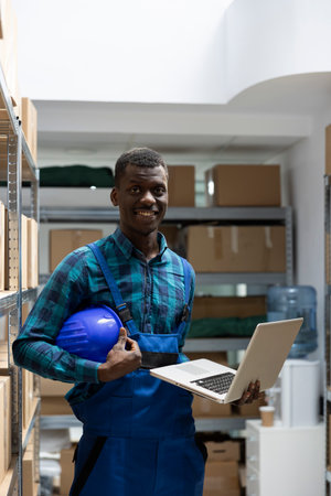 Black male employee examine labeled parcels on shelves in a storage unit depot. Logistics services support bulk shipping and retail inventory movement for supply chain, storehouse.の写真素材
