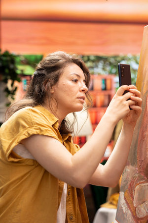 Woman painter recording a vlog to advertise her painting on social media channel, creating a self...