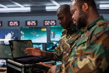 Counterintelligence colleagues combating terrorism using detection system on laptop. African american intelligence officer protecting national borders by tracking terrorists entering countryの写真素材