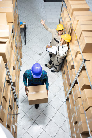 Diverse employees group preparing parcels and managing stock in an organized warehouse depot facility. Logistics center staff supports retail distribution and operational effectiveness.の写真素材
