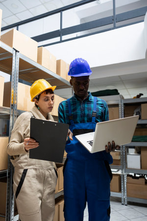 Factory operations rely on diverse warehouse team who handle products on racks, overseeing order transportation and organizing goods for effective inventory management and distribution.の写真素材
