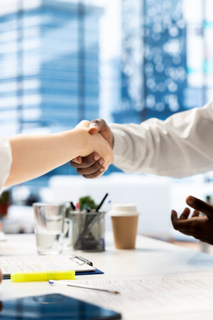 HR manager reaching agreement with job candidate after finishing background checks to job applicant. HR professional shaking hand with candidate for vacant startup business positionの写真素材