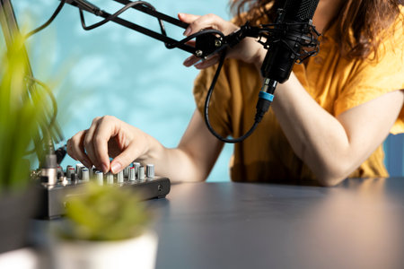 Content creator checking mic is properly calibrated, ensuring it captures clear audio for upcoming video. Close up of influencer checking audio levels, making adjustments to balance soundの写真素材