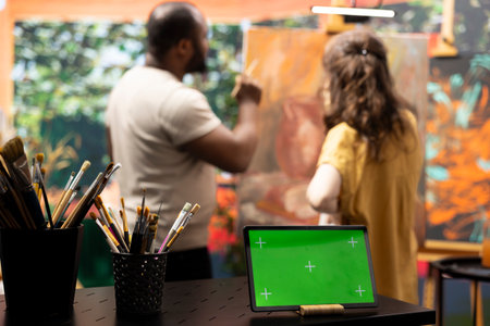 Team of painters working together on a artwork next to isolated mockup in atelier, painting with watercolor and brushes. Diverse artists creating a new masterpiece for the gallery.の写真素材